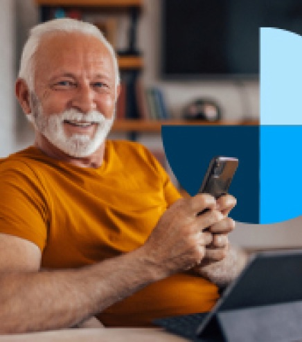 An older man smiling while using his phone at home