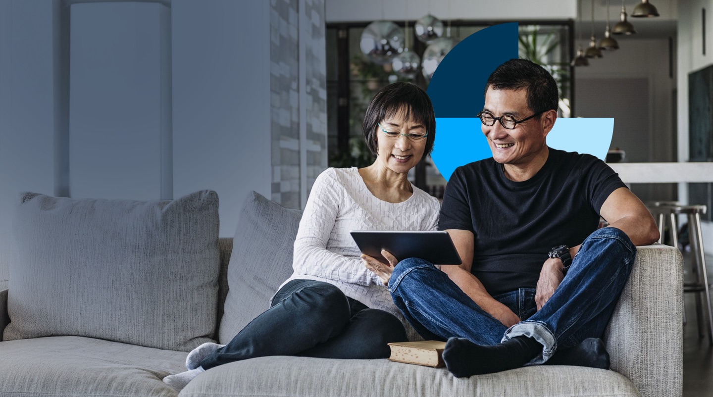 A couple sitting on a couch looking at a tablet together