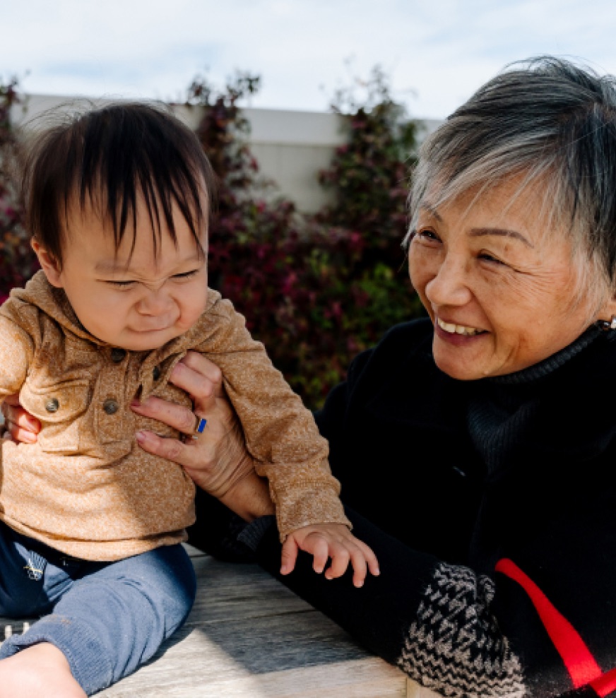 A grandmother laughing with her grandchild outdoors